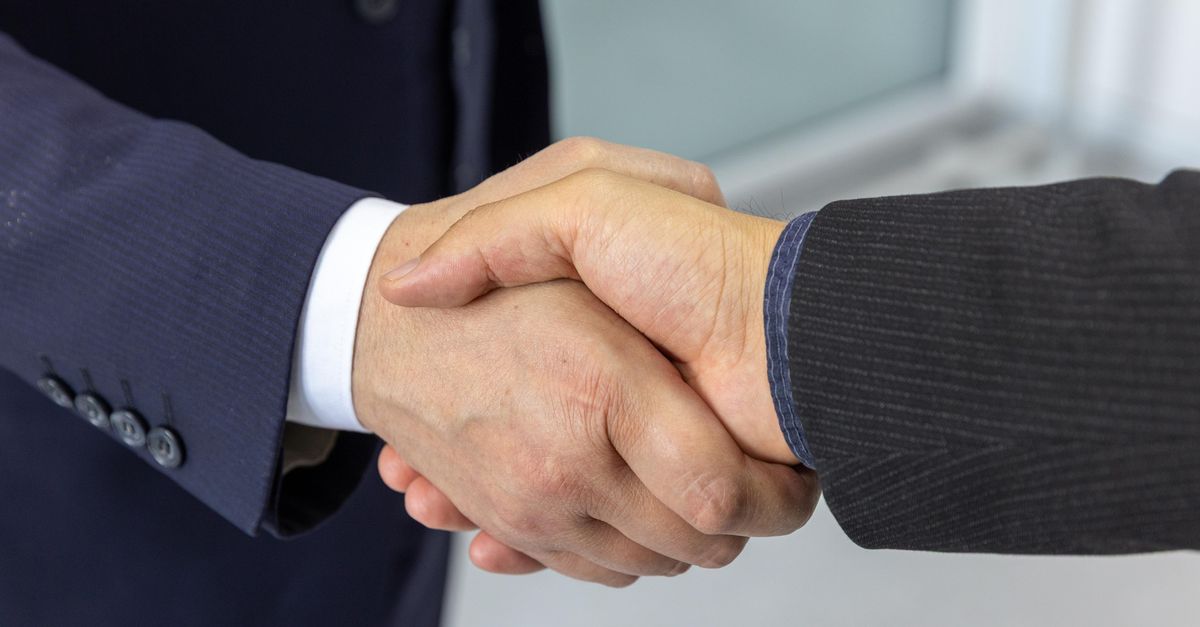 Close-up of two business professionals shaking hands, symbolizing partnership and collaboration.